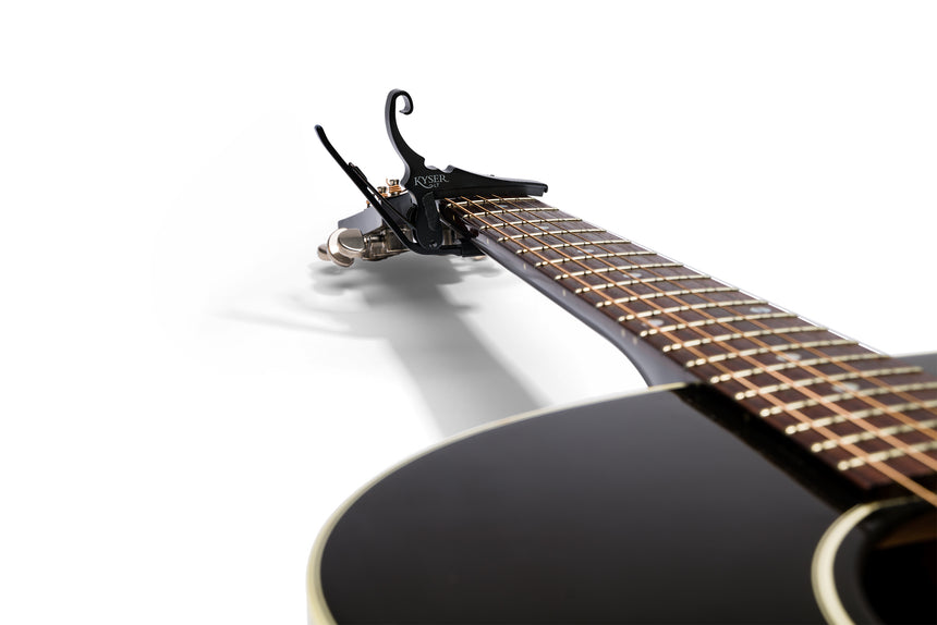 Capodastre Kyser KG6LTA noir à faible tension pour guitare acoustique – monté sur le manche d’une guitare acoustique.