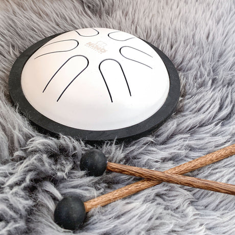 Mini steel tongue drum NINO980WH blanche avec bord noir et deux mailloches sur une fourrure
